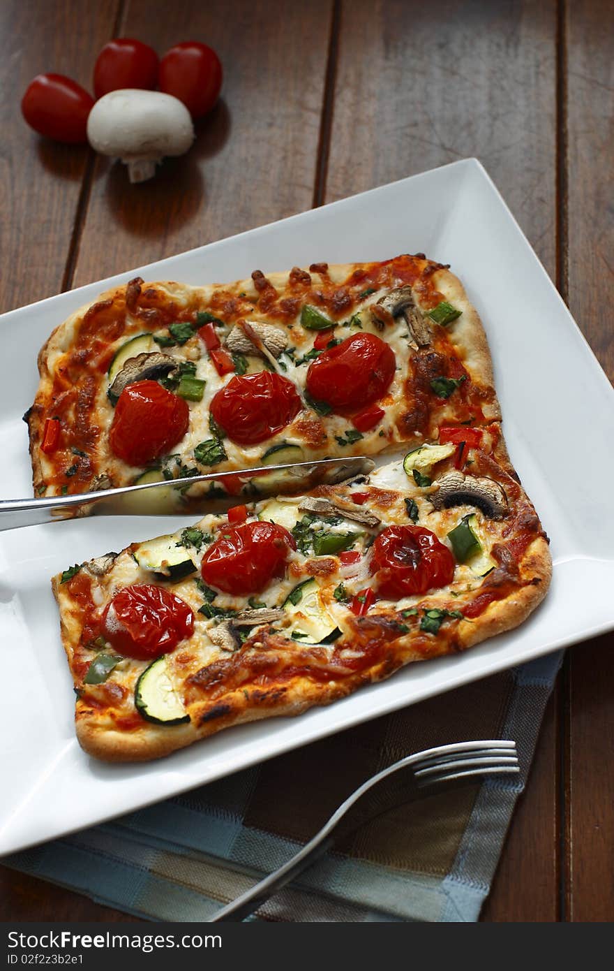 Vegetarian pizza on a white plate with fork and knife utensil. Vegetarian pizza on a white plate with fork and knife utensil.