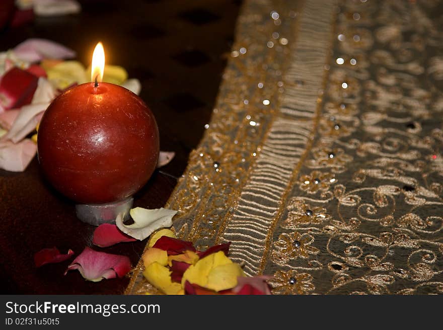 Red ball candle surrounded by rose petals in various colours