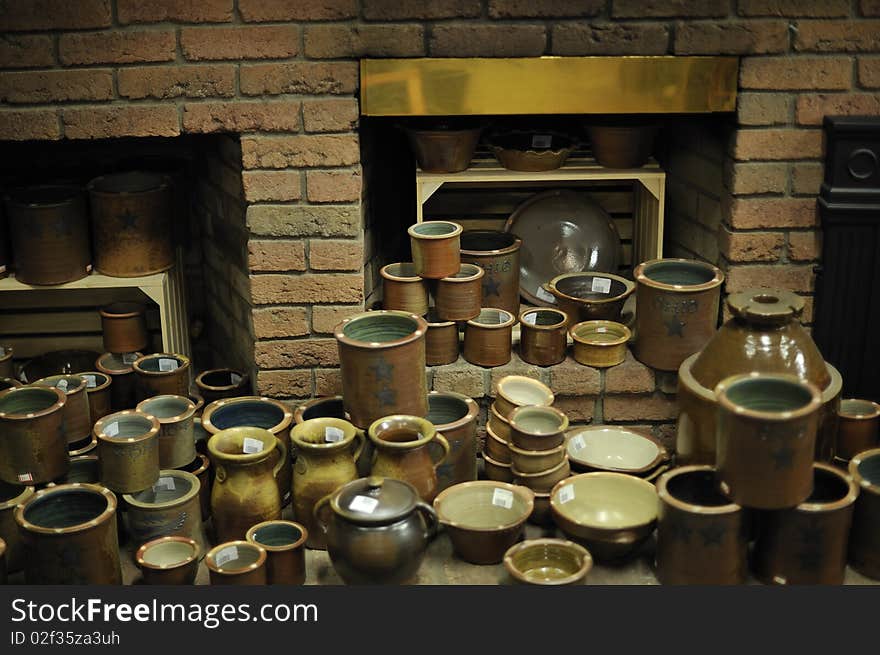 Variety of finished pottery arranged in front of brick fireplace in a kiln room. Horizontal shot. Variety of finished pottery arranged in front of brick fireplace in a kiln room. Horizontal shot.