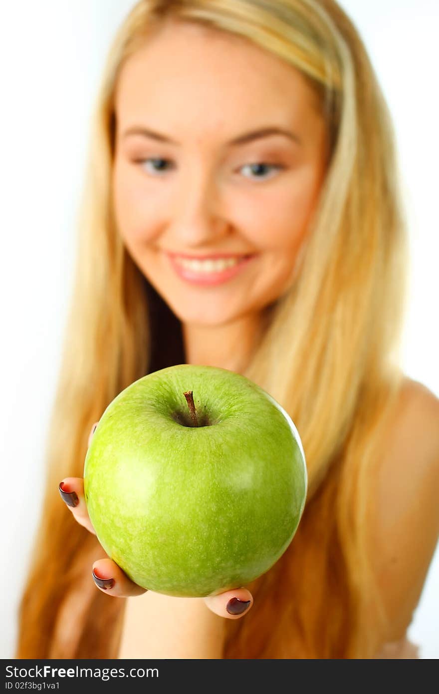 Young woman holding an apple into the camera - focus on apple. Young woman holding an apple into the camera - focus on apple