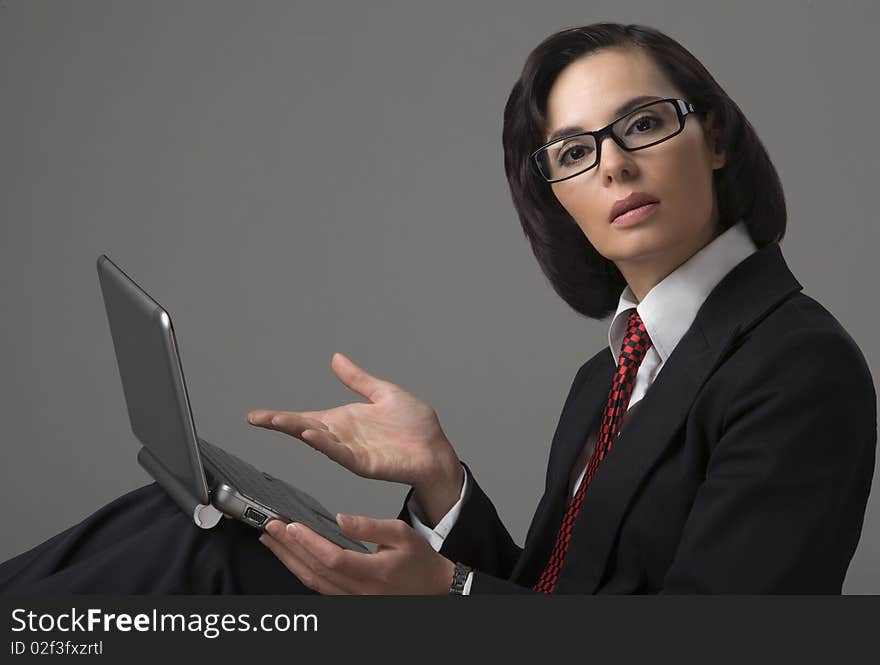 Portrait of the business woman on a grey background with the laptop