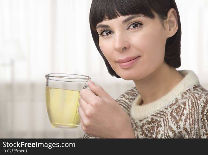 The young woman holds in hand a cup with green tea. The young woman holds in hand a cup with green tea