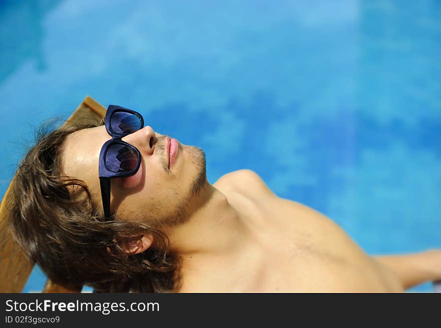 Man tanning poolside on a summer day. Man tanning poolside on a summer day