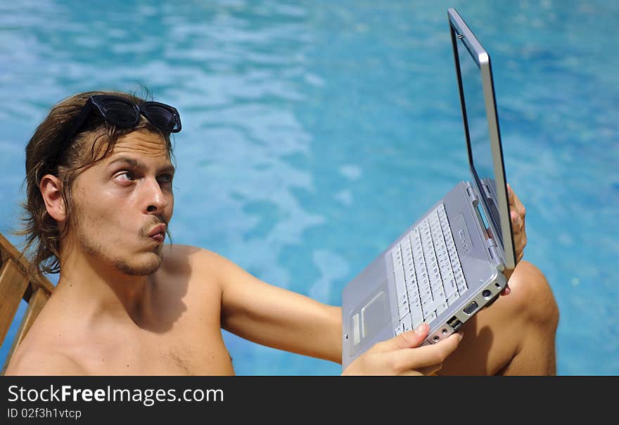 Man looks into his webcam while sitting poolside. Man looks into his webcam while sitting poolside