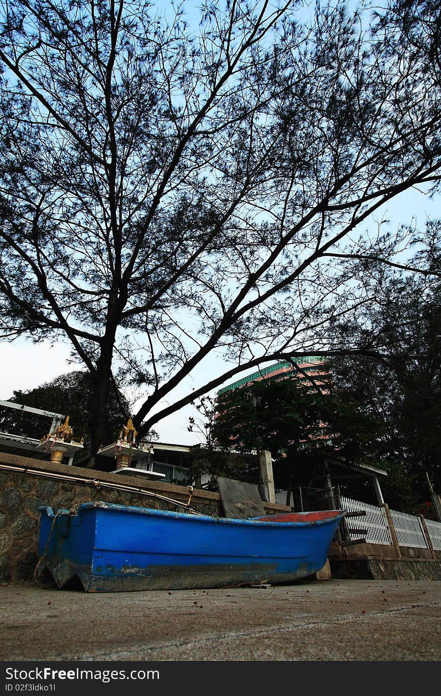 Blue boat on the land under the tree.