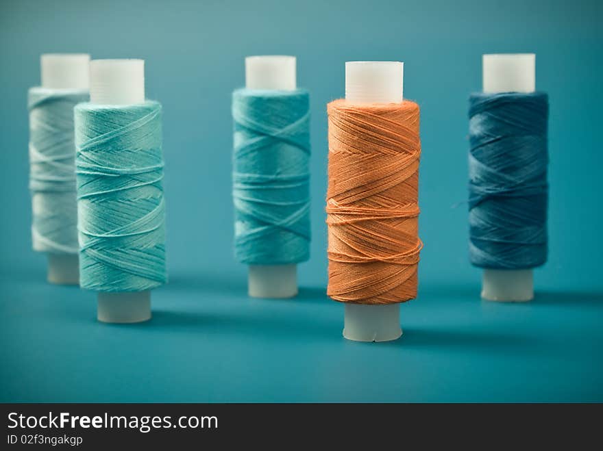 Upright colored spools of thread on a blue background