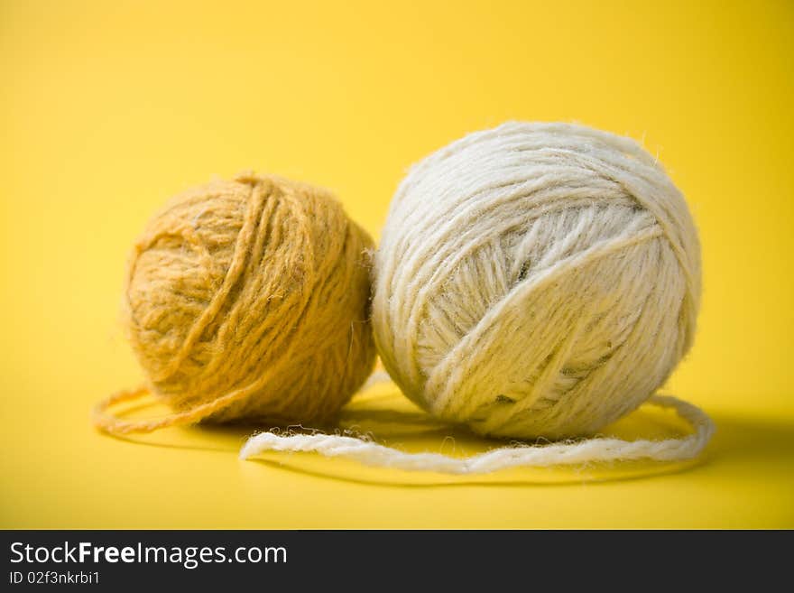 White and yellow balls of yarn on a yellow background