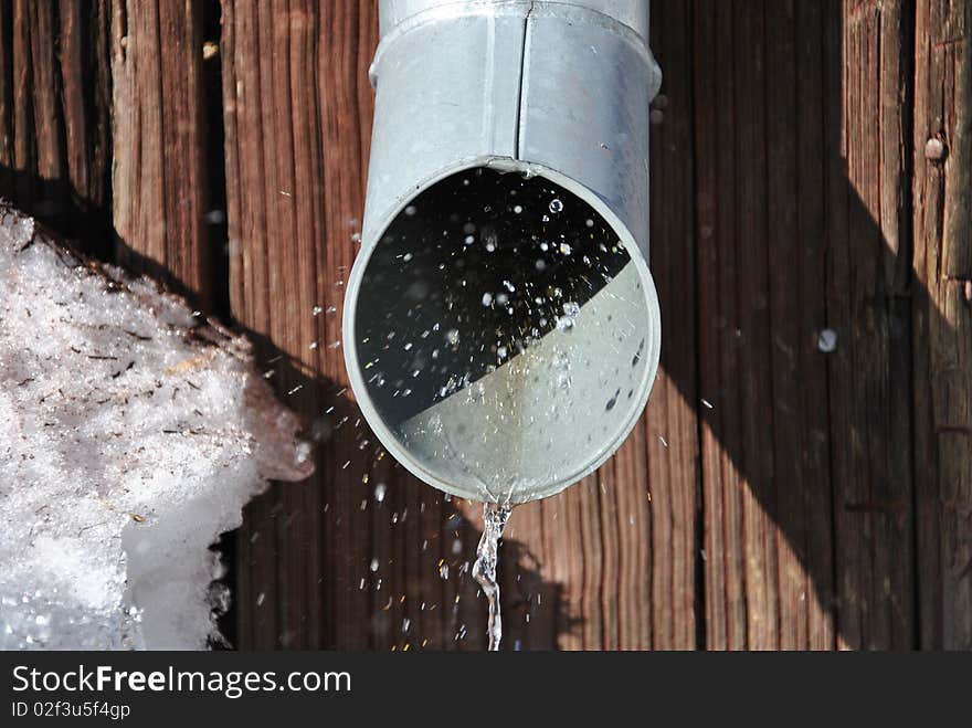 Melted snow is coming out from the pipe. Melted snow is coming out from the pipe