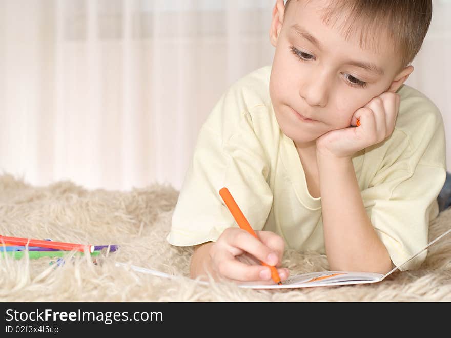 Young kid with pencils on the carpet