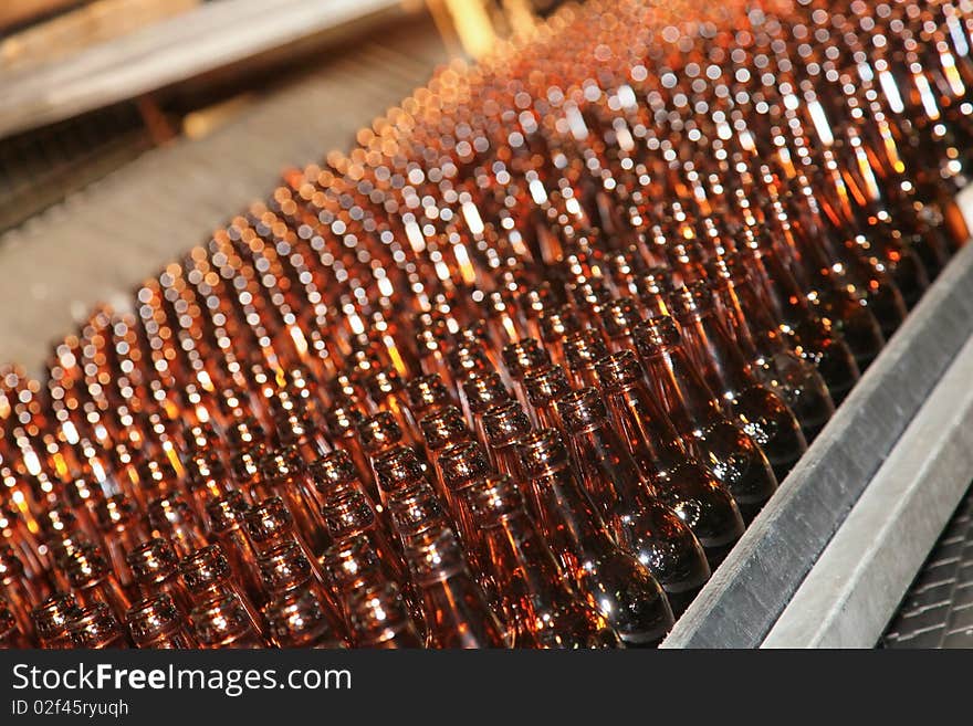 Conveyer line with many brown beer bottles in a plant workshop. Conveyer line with many brown beer bottles in a plant workshop