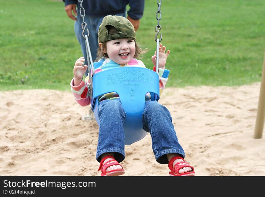 A cute, happy, smiling, young girl on a swing at a park. A cute, happy, smiling, young girl on a swing at a park.
