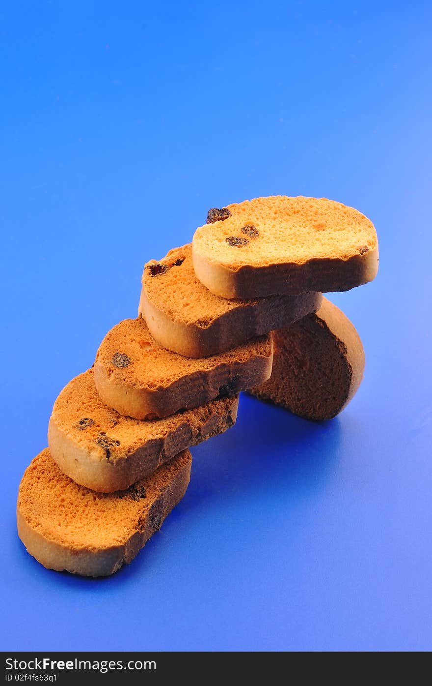 Deep fried bread with raisins lined up in the form of steps in front of blue background. Deep fried bread with raisins lined up in the form of steps in front of blue background