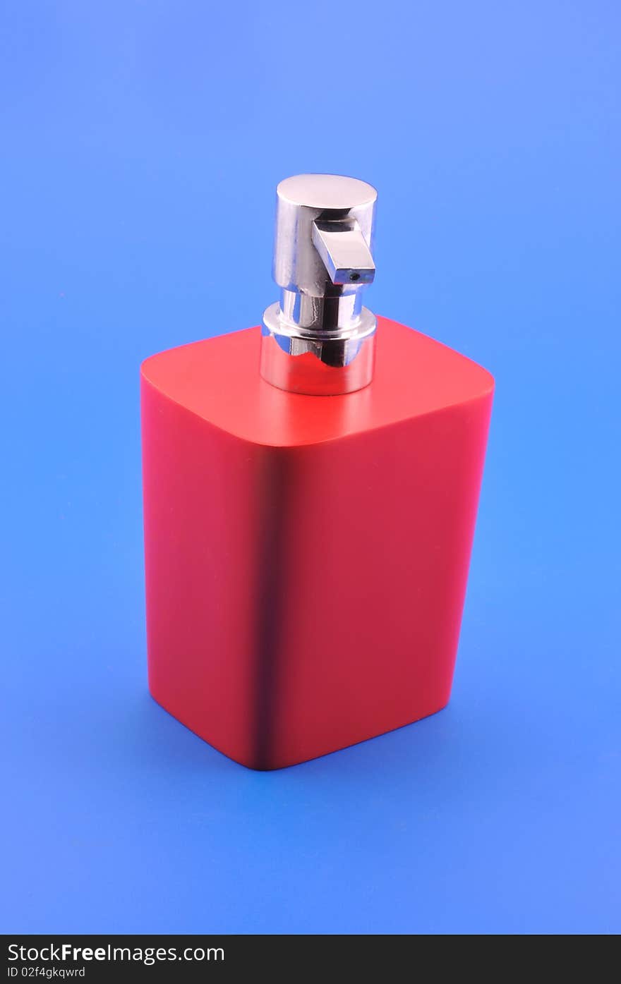 Dispenser for liquid soap red photographed in front of blue background