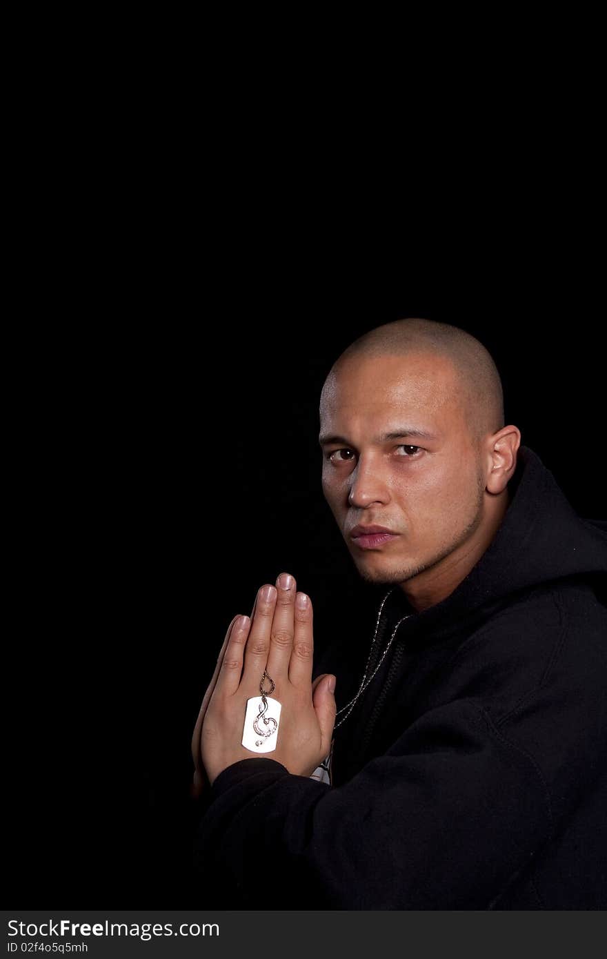 A young asian man with a hoddie is praying over black. A young asian man with a hoddie is praying over black