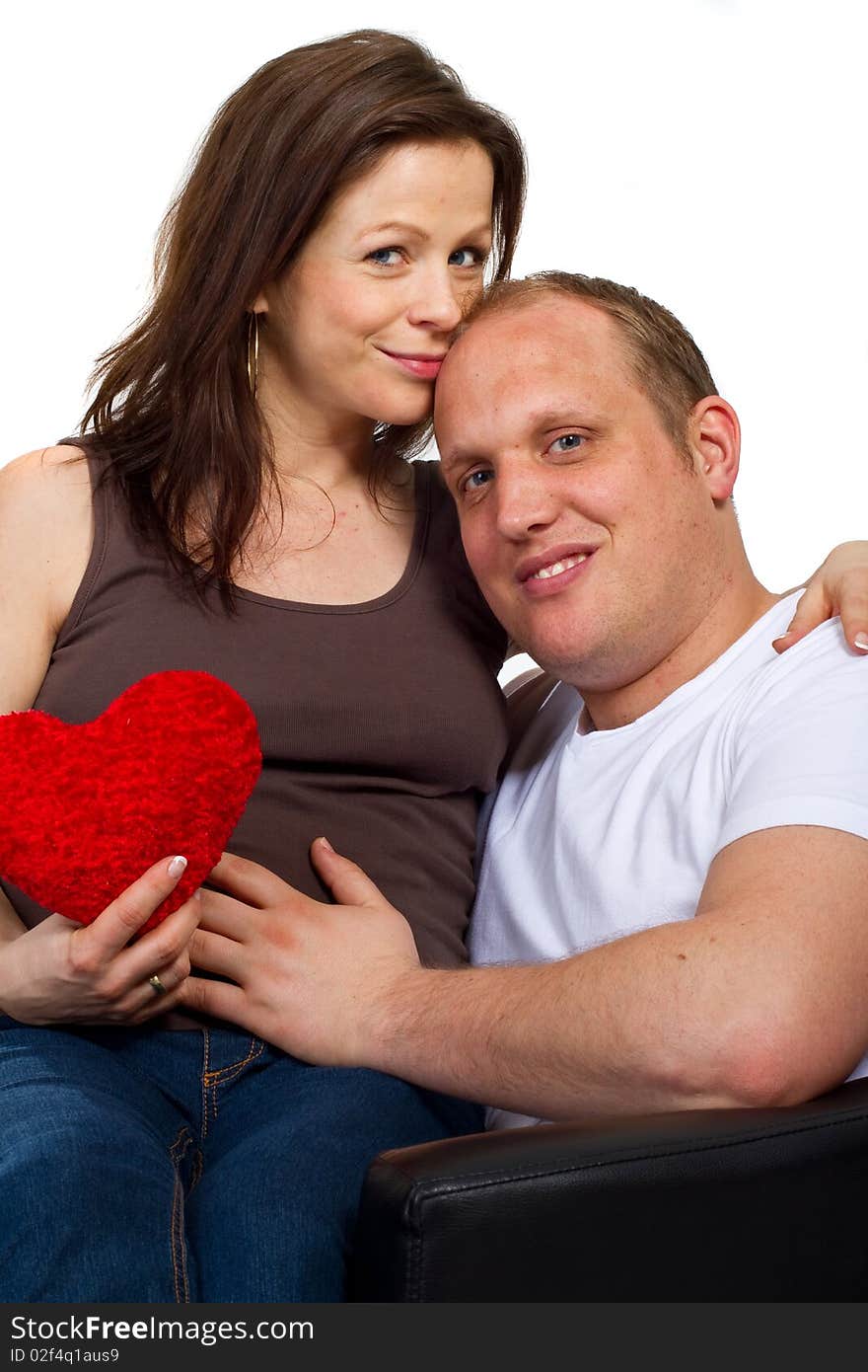 Young couple sitting in a chair holding a heart. Young couple sitting in a chair holding a heart.