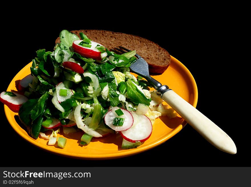 Salad in a yellow plate on a black background