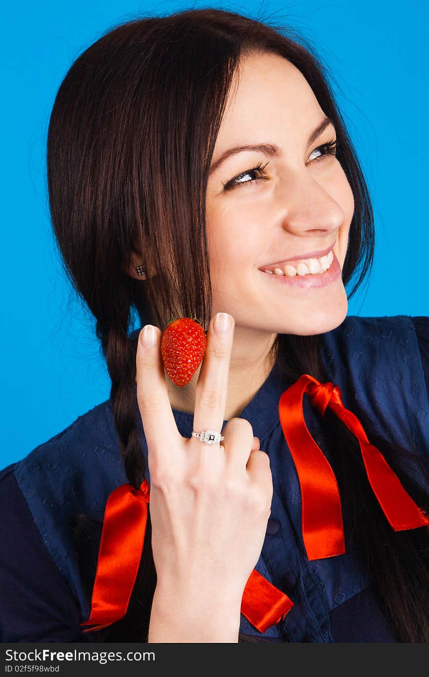 Beautiful lady holding a strawberry, studio shot on blue background