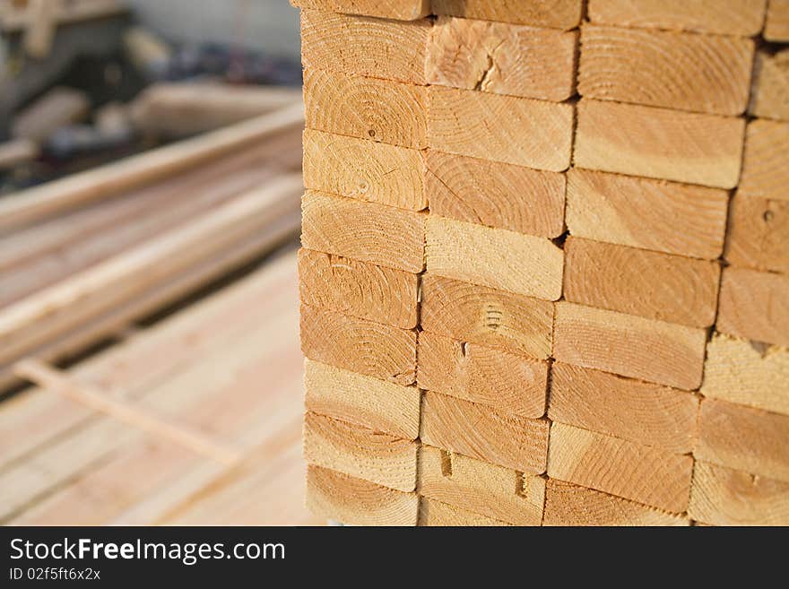 Selective focus image of stacks of 2x4 boards at a construction site, with more lumber visible in the background. Horizontal shot. Selective focus image of stacks of 2x4 boards at a construction site, with more lumber visible in the background. Horizontal shot.