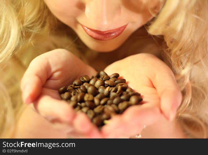 Beautiful girl with long blonde hair holding in hands coffee beans