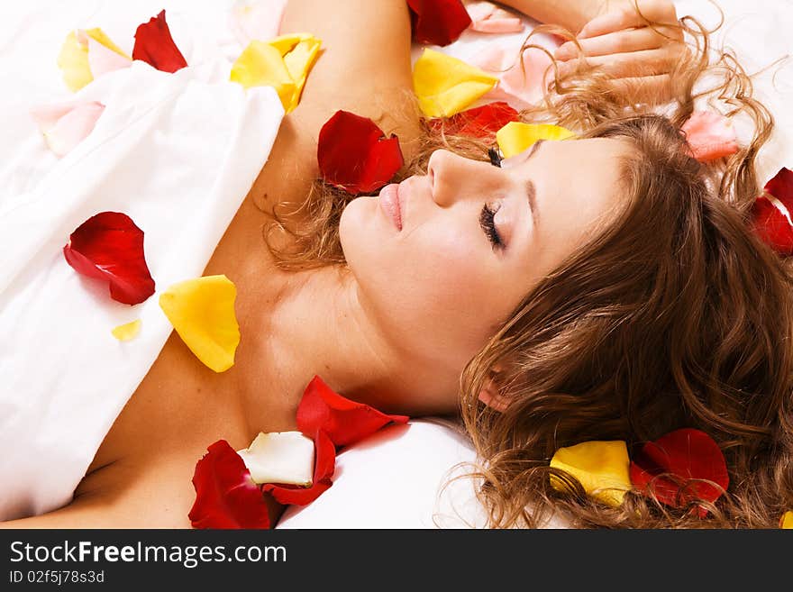 Beautiful young woman lying in rose petals