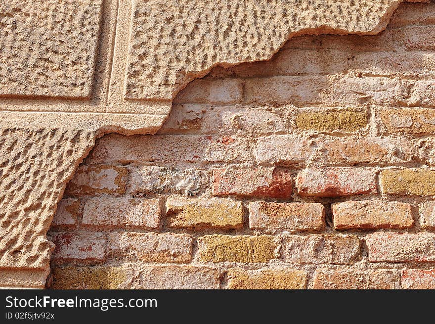 Partly covered old brick wall with some of the decorative cementwork still showing.