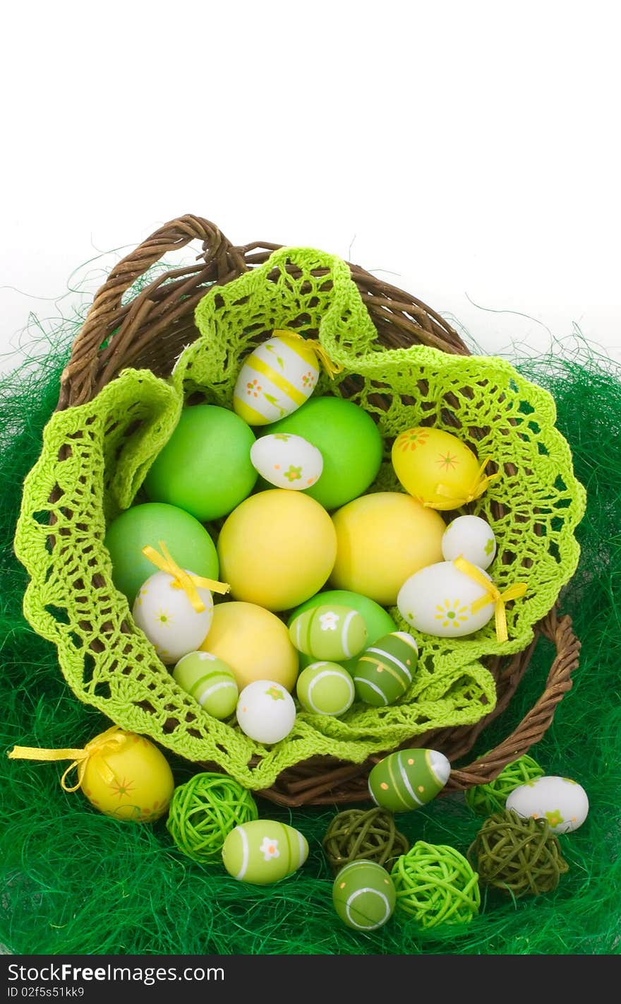 Colorful painted Easter eggs in the basket on green grass isolated on white background