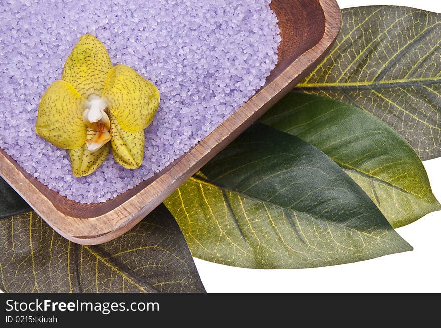 Orchid in a bowl of purple bath salts isolated on a leaf background. Orchid in a bowl of purple bath salts isolated on a leaf background.