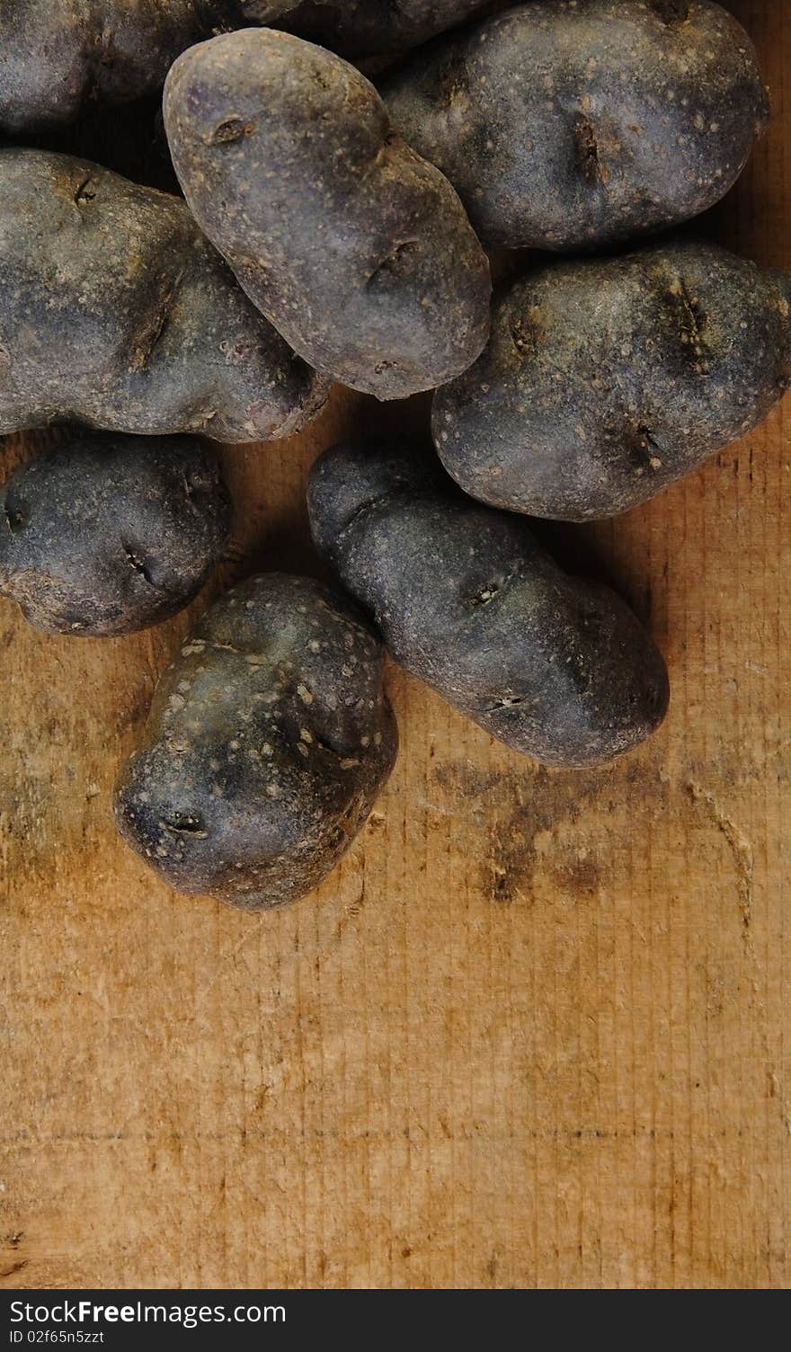 Purple fingerling potatoes on a rustic wooden table.