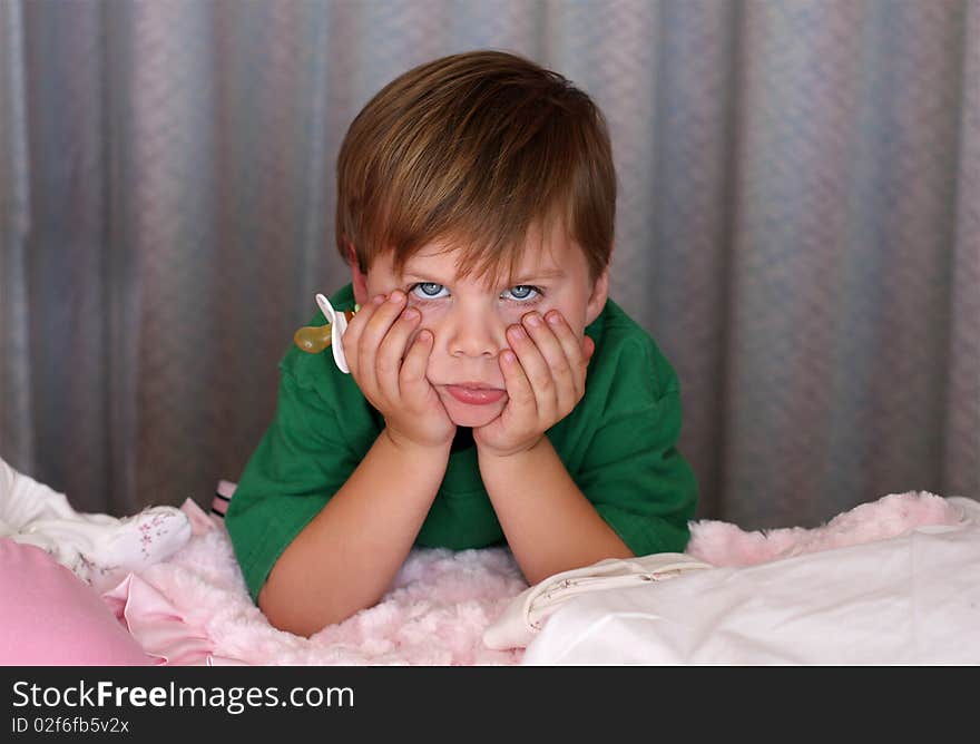 Funny photo of a unhappy boy holding his sisters pacifier. Funny photo of a unhappy boy holding his sisters pacifier