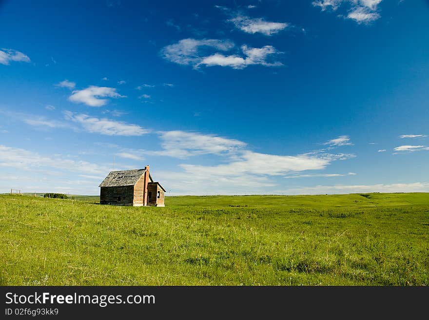 Wood building with brick chimney in green pasture against blue sky with some cloud. Wood building with brick chimney in green pasture against blue sky with some cloud.