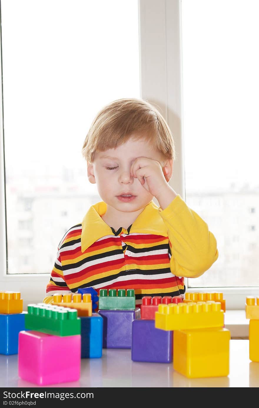 The beautiful little boy poses on a light background. The beautiful little boy poses on a light background