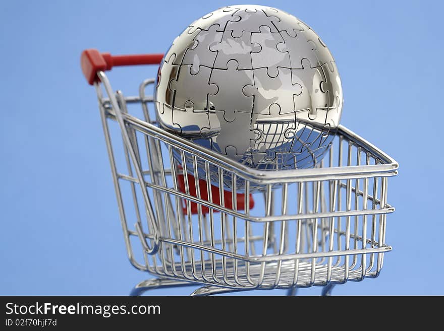 Metal puzzle globe with shopping cart on blue background