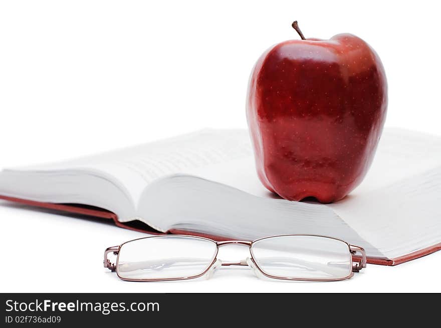 Red apple and glasses on the book isolated over white