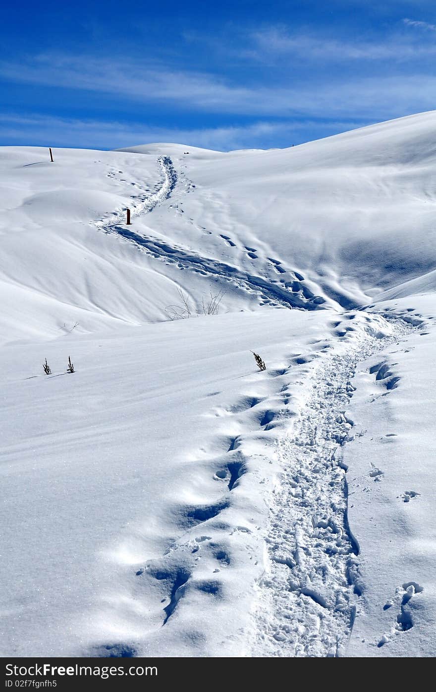 Lane on snow in the mountain going far away in the blue sky