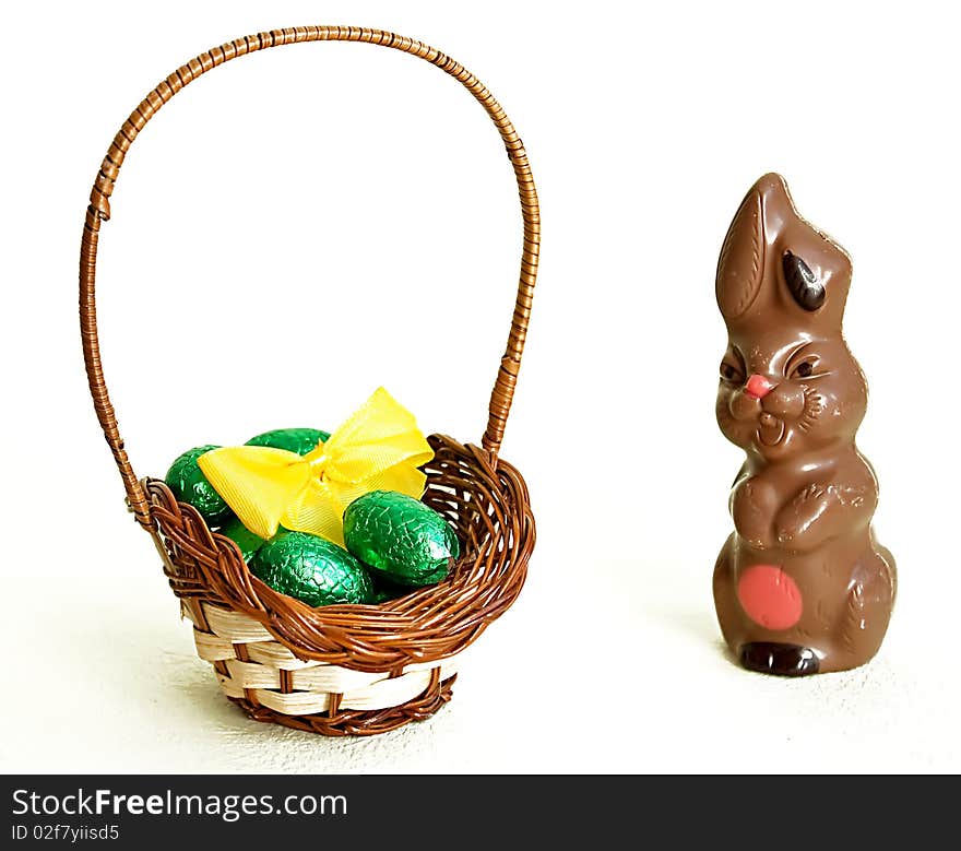 Milk chocolate Easter bunny and basket with chocolate eggs on white background. Milk chocolate Easter bunny and basket with chocolate eggs on white background