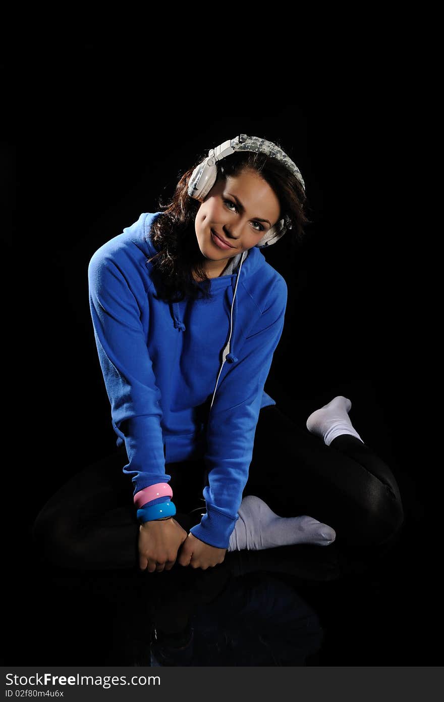 Young woman listening to music on a black background