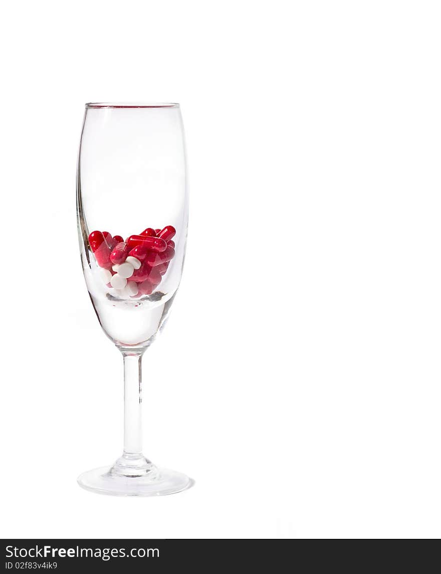 Glass with red both white tablets and pills isolated on white. Glass with red both white tablets and pills isolated on white