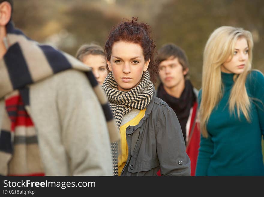 Teenage Girl Surrounded By Friends In Outdoor Autumn Landscape