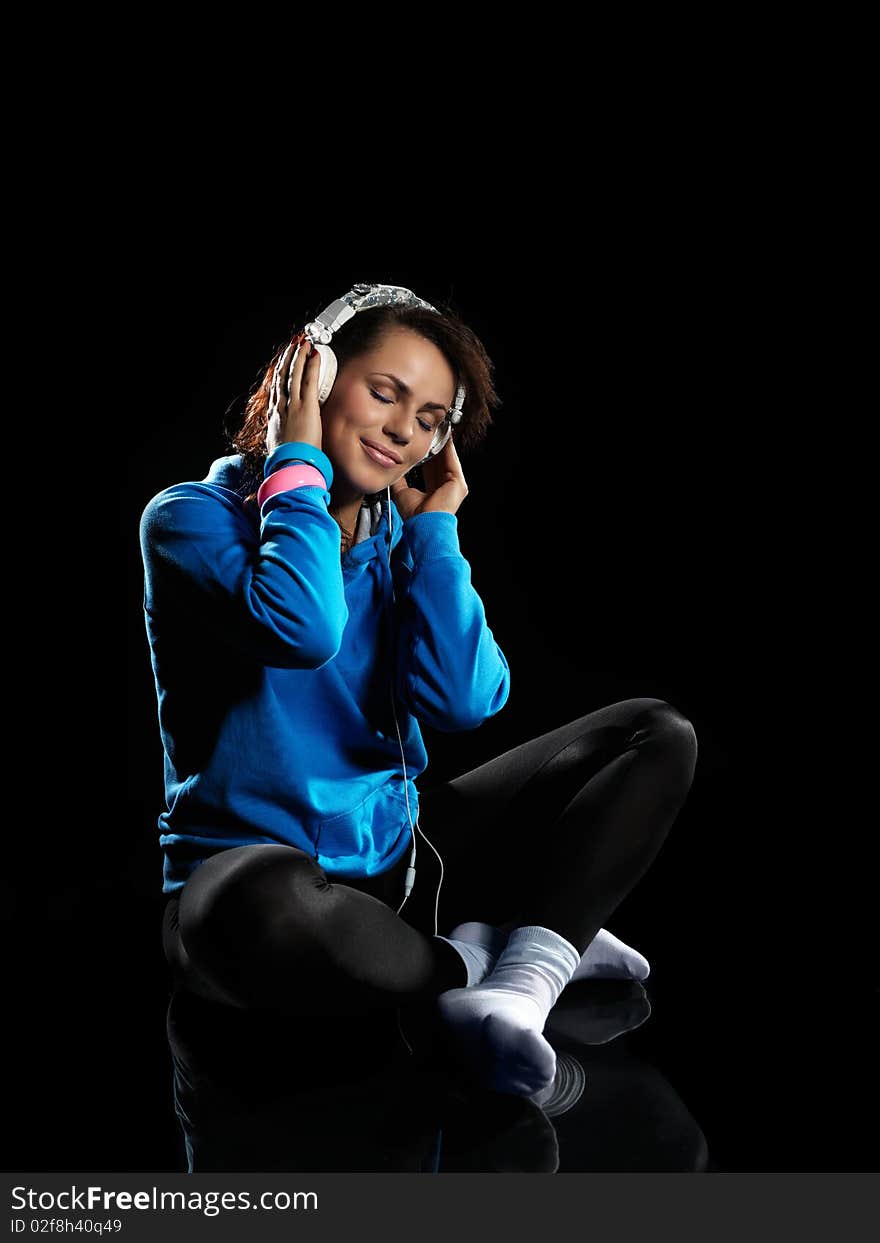 Young woman listening to music on a black background