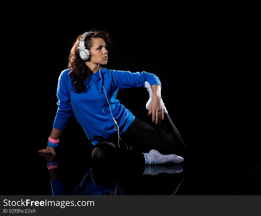 Young woman listening to music on a black background