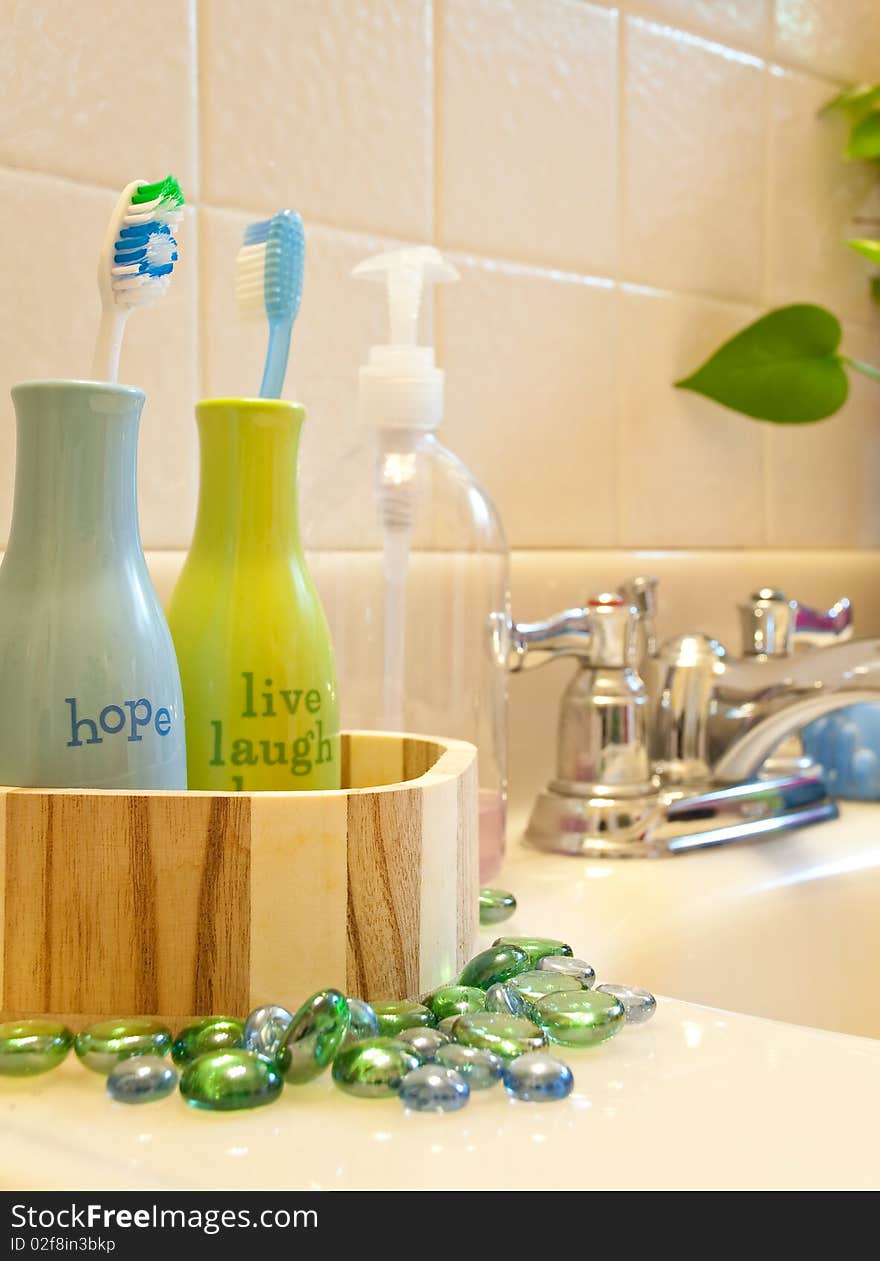 Inspiration word bottles holding toothbrushes with colorful beads for a bathroom sink presentation. Inspiration word bottles holding toothbrushes with colorful beads for a bathroom sink presentation.