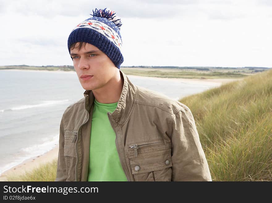 Teenage Boy Standing In Sand Dunes Wearing Woolly Hat