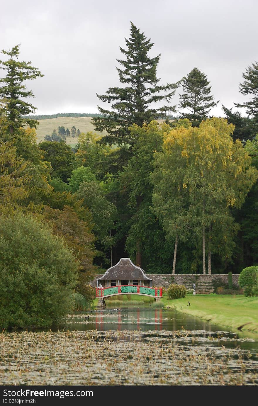 An oriental style bridge crosses over an ornamental pond in the gardens of a Scottish castle. An oriental style bridge crosses over an ornamental pond in the gardens of a Scottish castle.