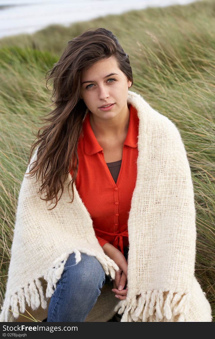 Young Woman Standing In Sand Dunes Wrapped In Blanket