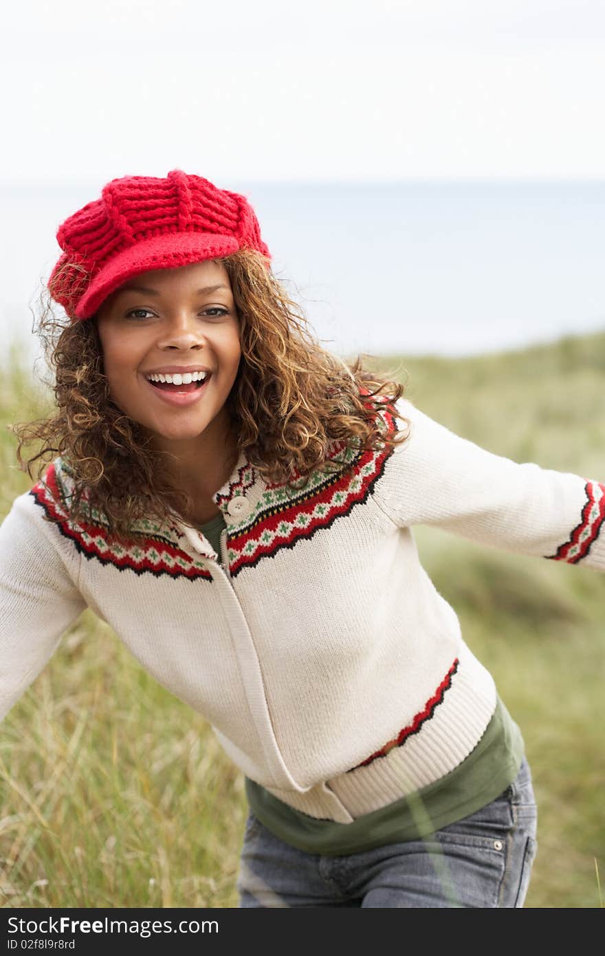 Teenage Girl Walking Through Sand Dunes Wearing Warm Clothing