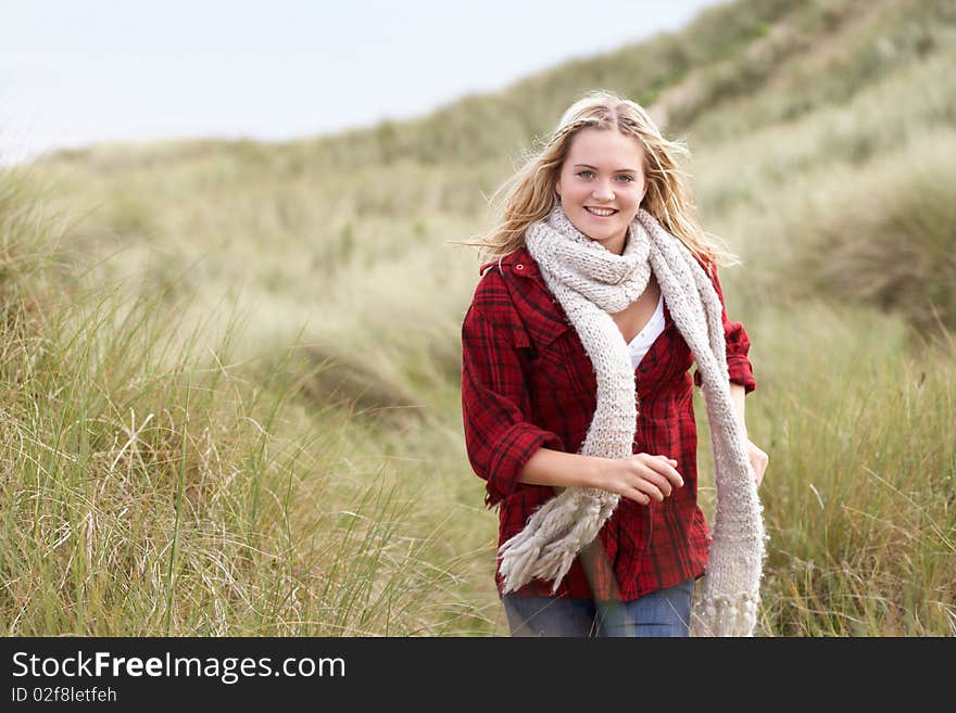 Teenage Girl Walking Through Sand Dunes Wearing Warm Clothing