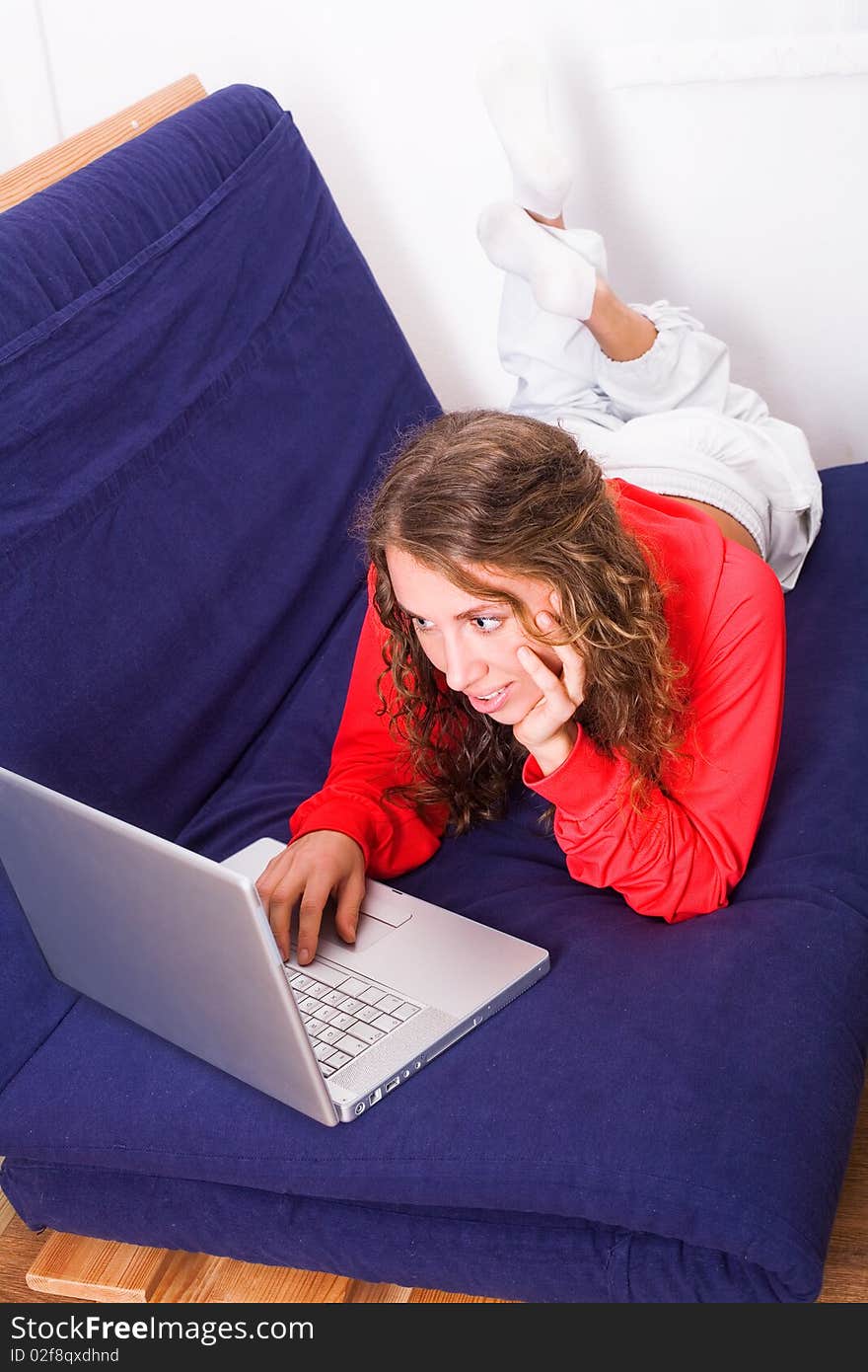 Nice girl work on laptop lying on the sofa. Nice girl work on laptop lying on the sofa