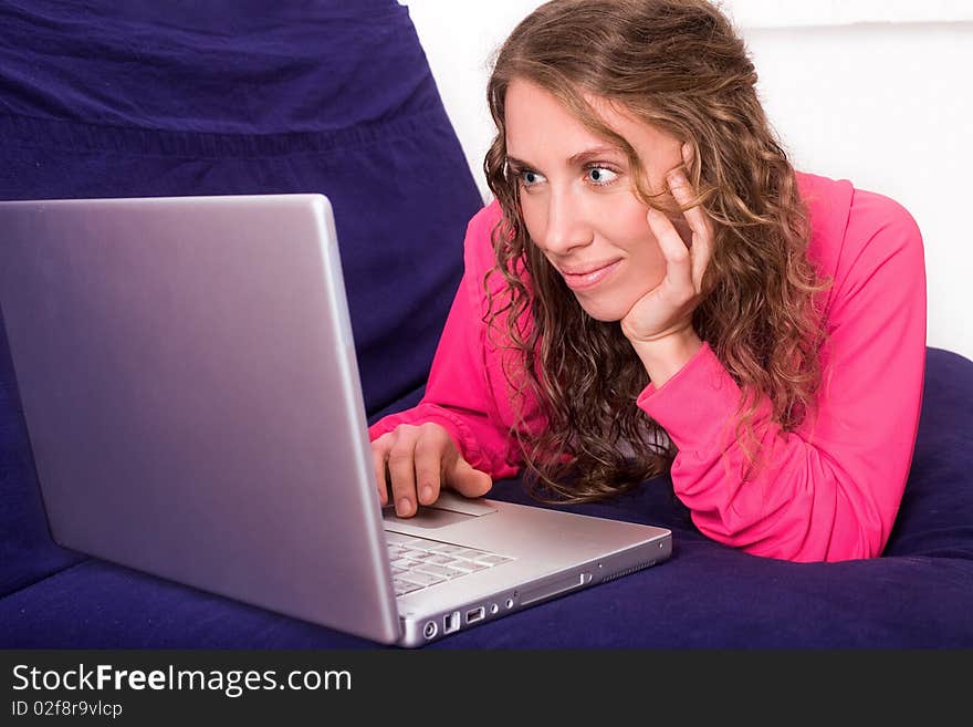 Young woman looks at laptop lying on the sofa. Young woman looks at laptop lying on the sofa