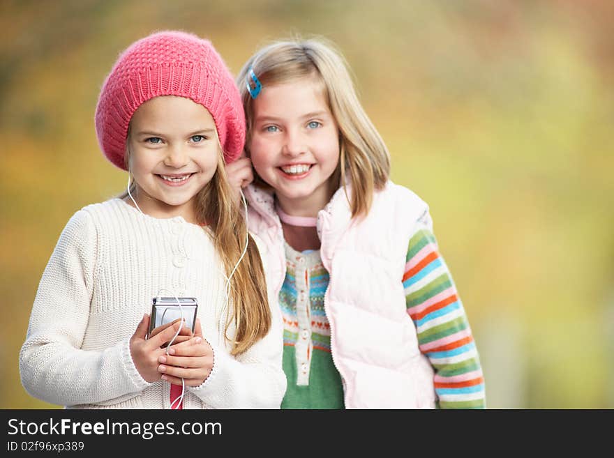 Two Young Girl Outdoors With MP3 Player Smiling At Camera