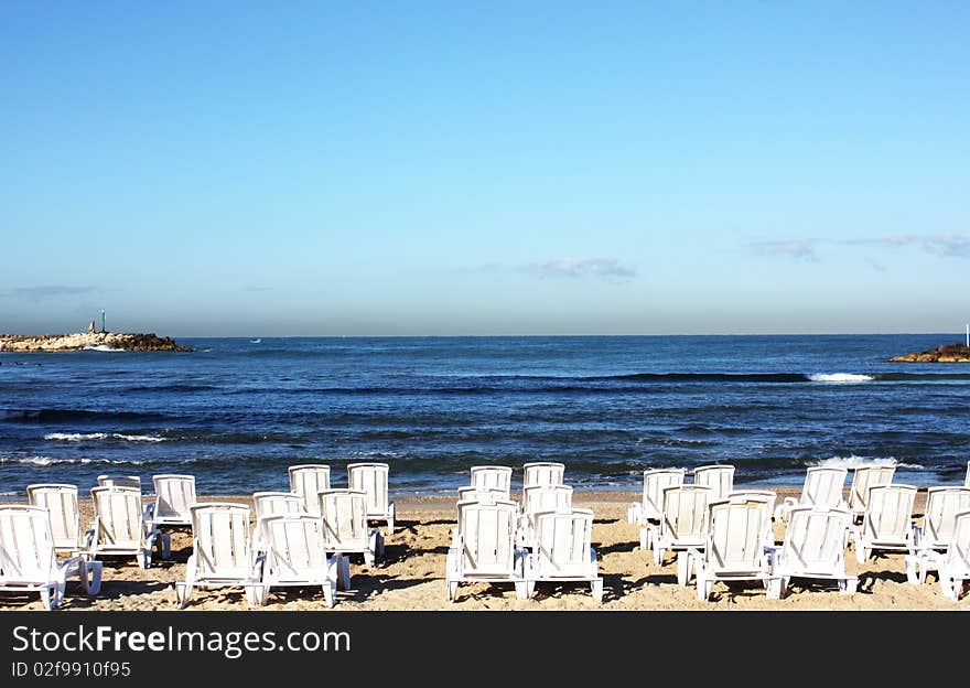 White deck chairs on the background of blue sea. White deck chairs on the background of blue sea